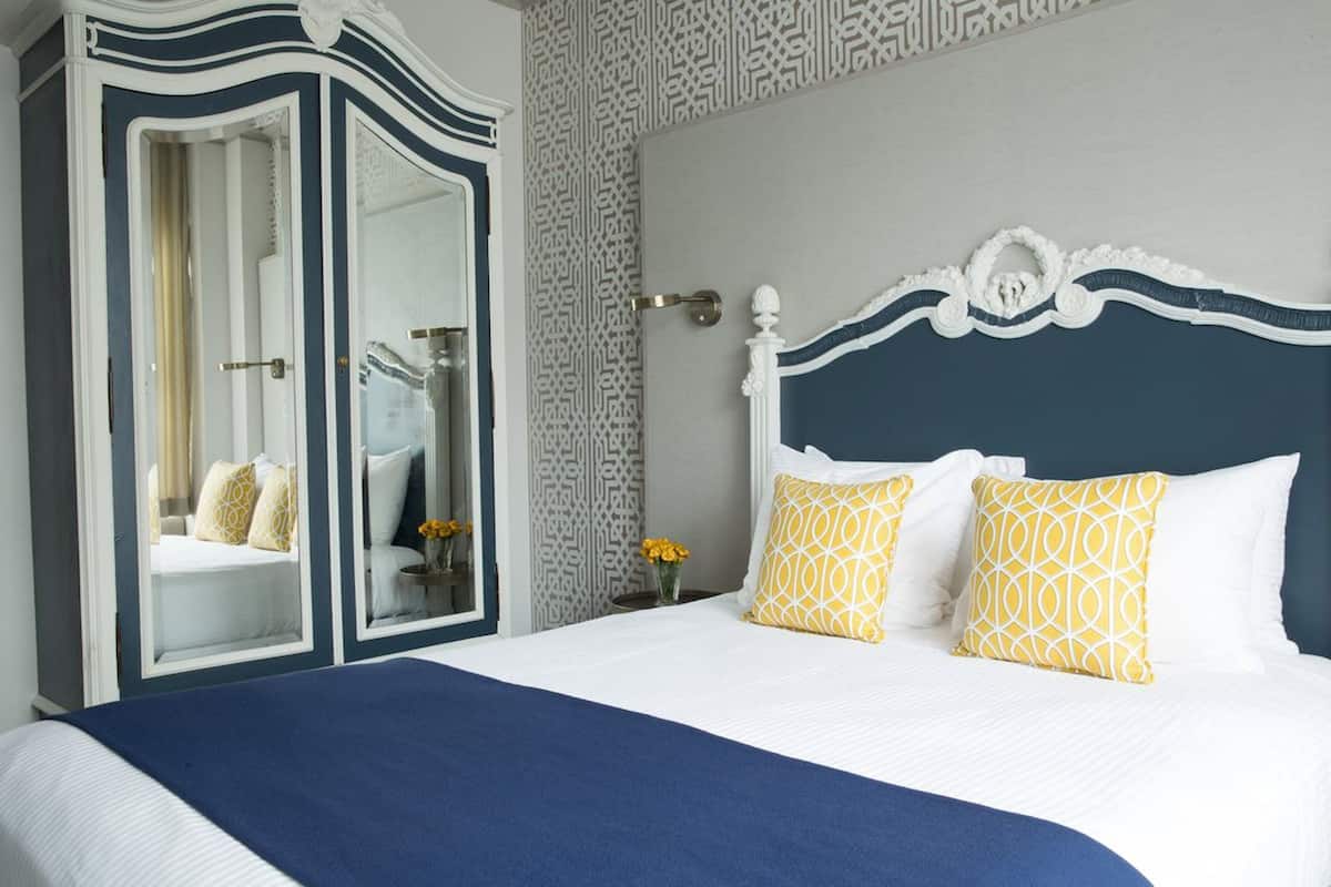 A bedroom with a large bed, a wardrobe, and a mirror.