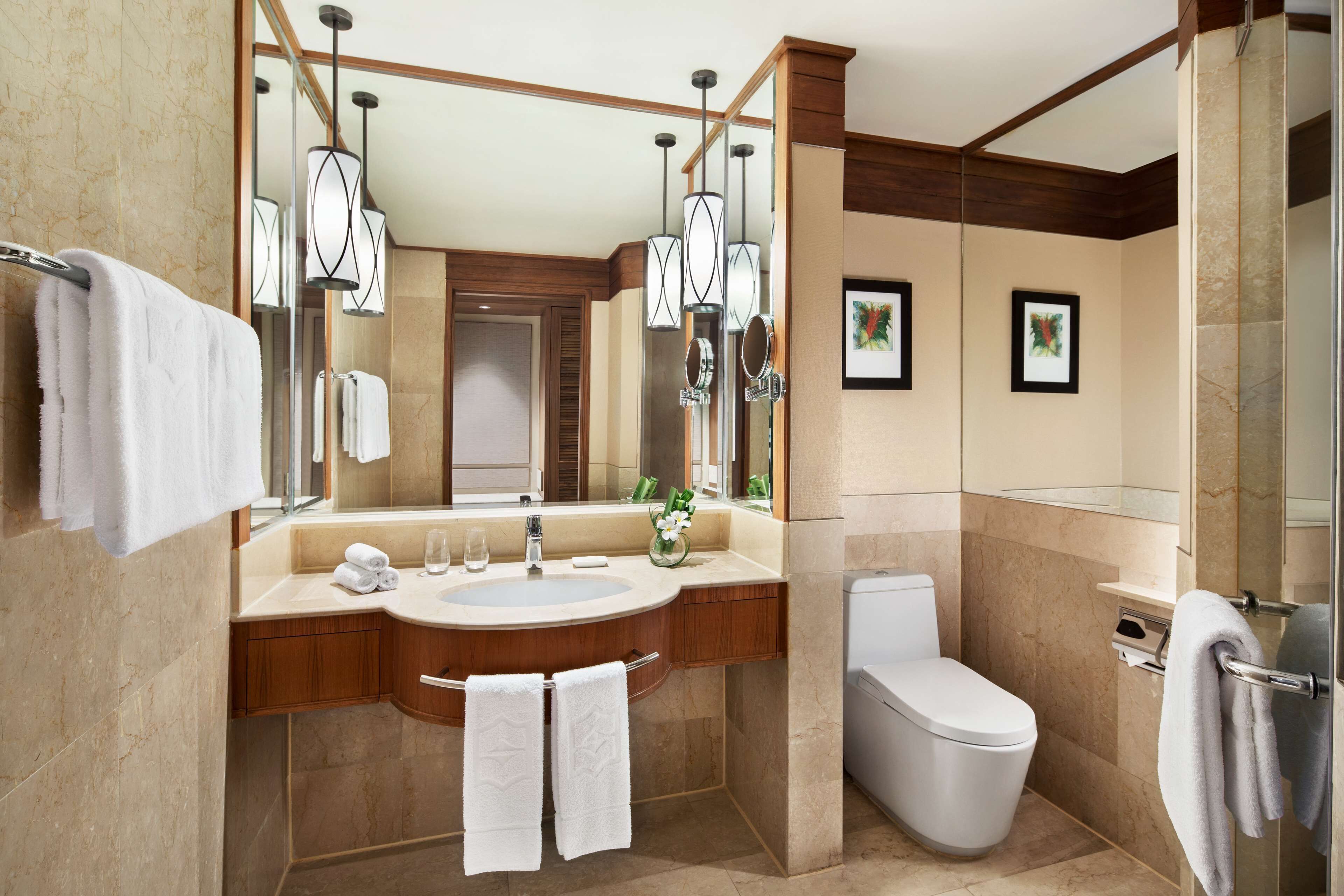 A modern bathroom with a large mirror, a sink, a toilet, and a shower.