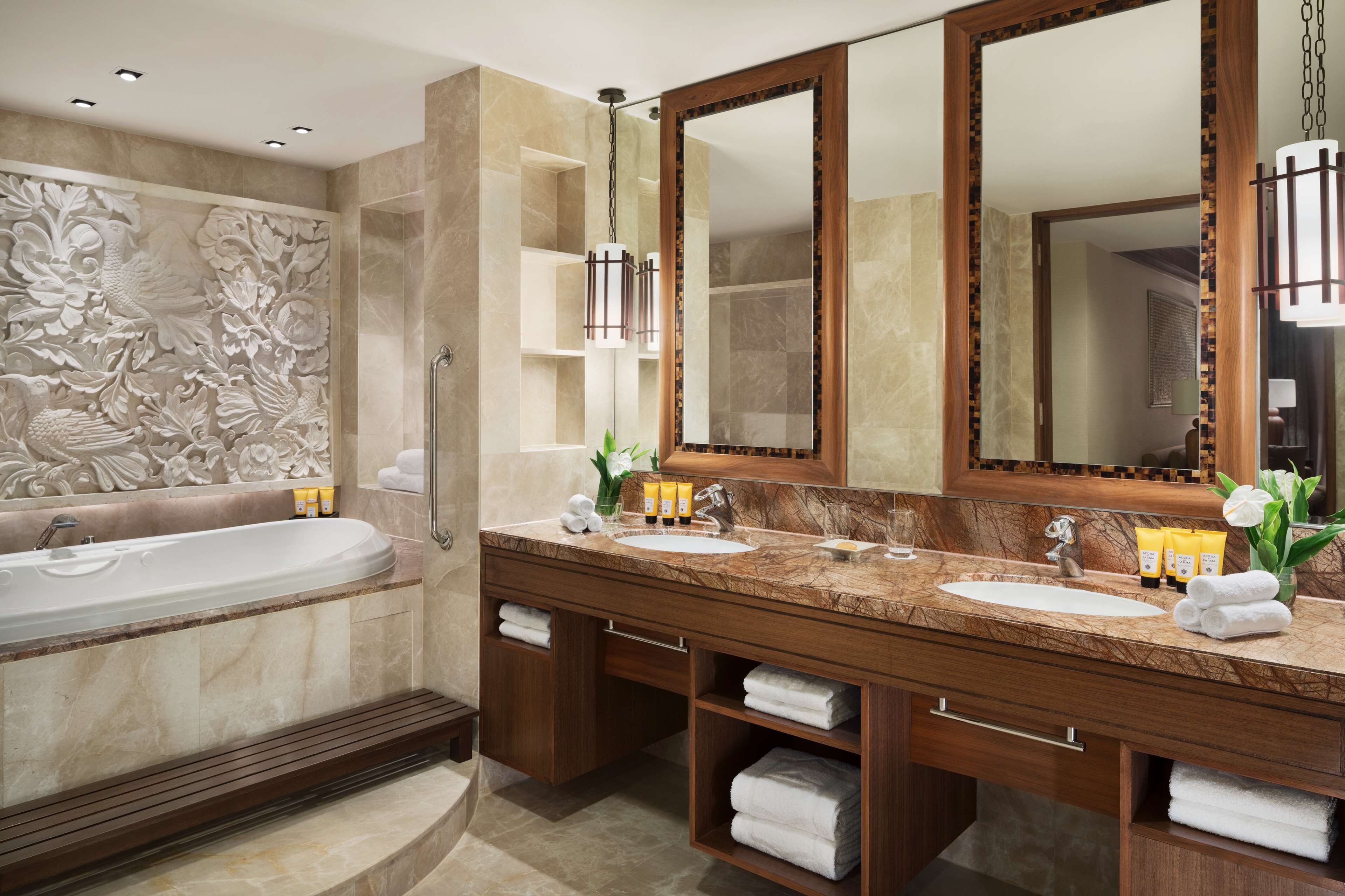 A modern bathroom with a large bathtub, two sinks, and a large mirror.