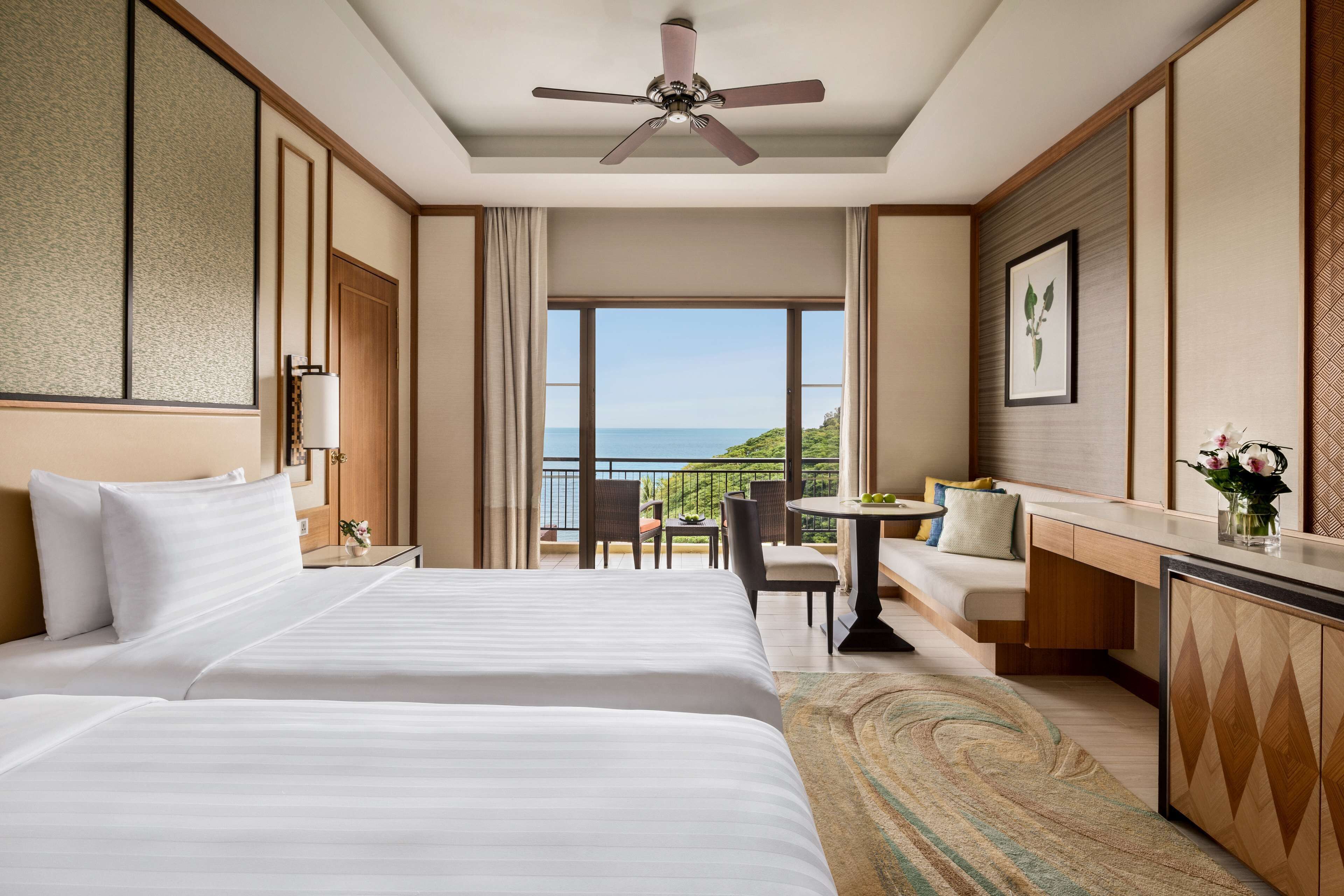 Habitación de hotel con una cama grande, un escritorio, una silla y vistas al mar.