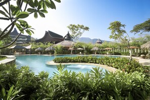 A swimming pool surrounded by lush greenery and traditional architecture.