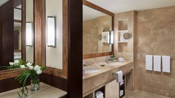 A modern bathroom with two sinks, a large mirror, and a vanity with a vase of flowers.