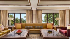 A spacious living room with a sofa set, two coffee tables, and a view of palm trees through large windows. - Shangri-La Rasa Sayang, Penang (George Town)