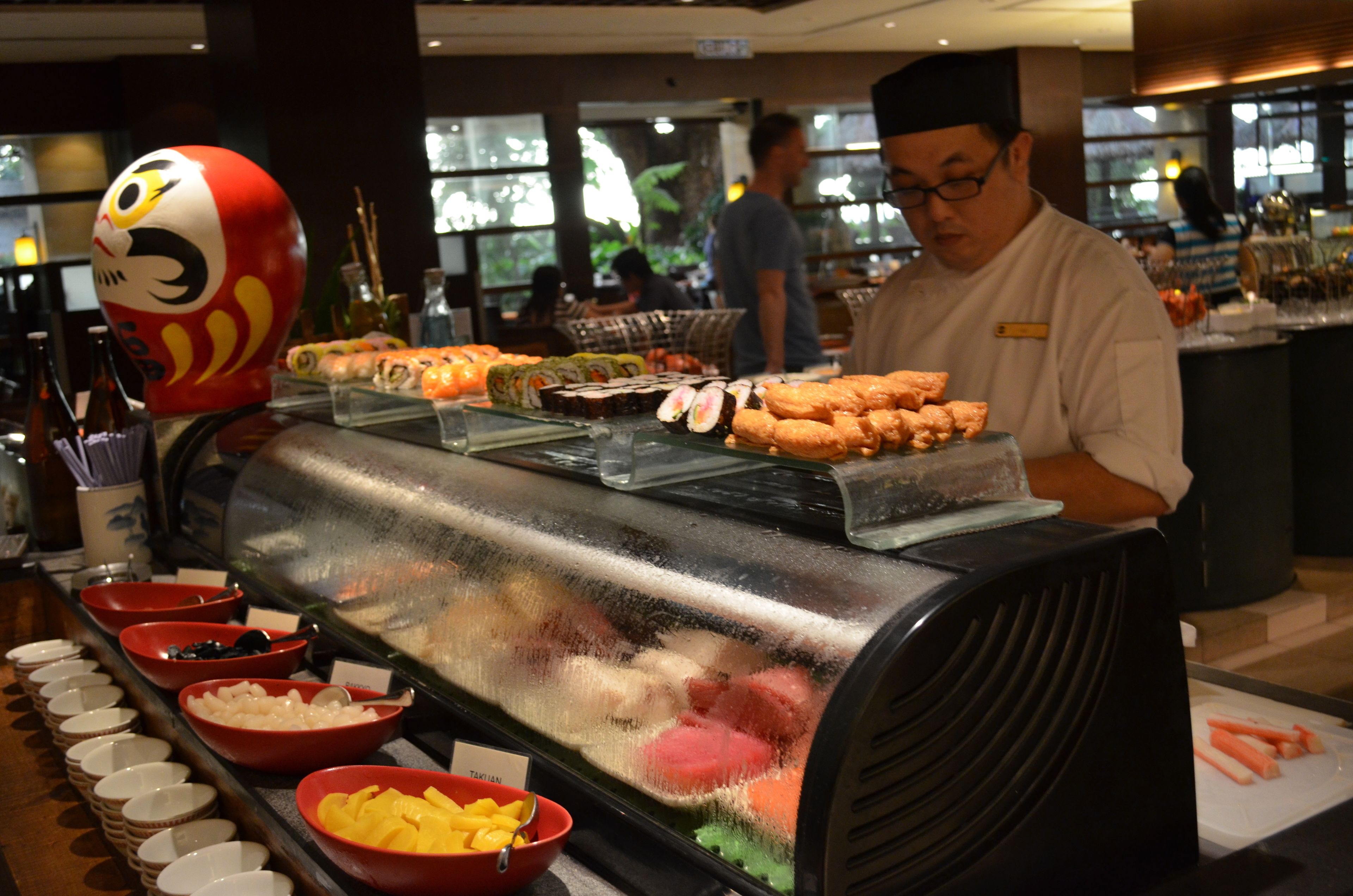 A buffet with various food items and a chef preparing food.