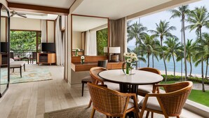 A modern hotel room with a balcony, a dining area with wicker furniture, a television, and a view of palm trees and the ocean. - Shangri-La Rasa Sayang, Penang (George Town)