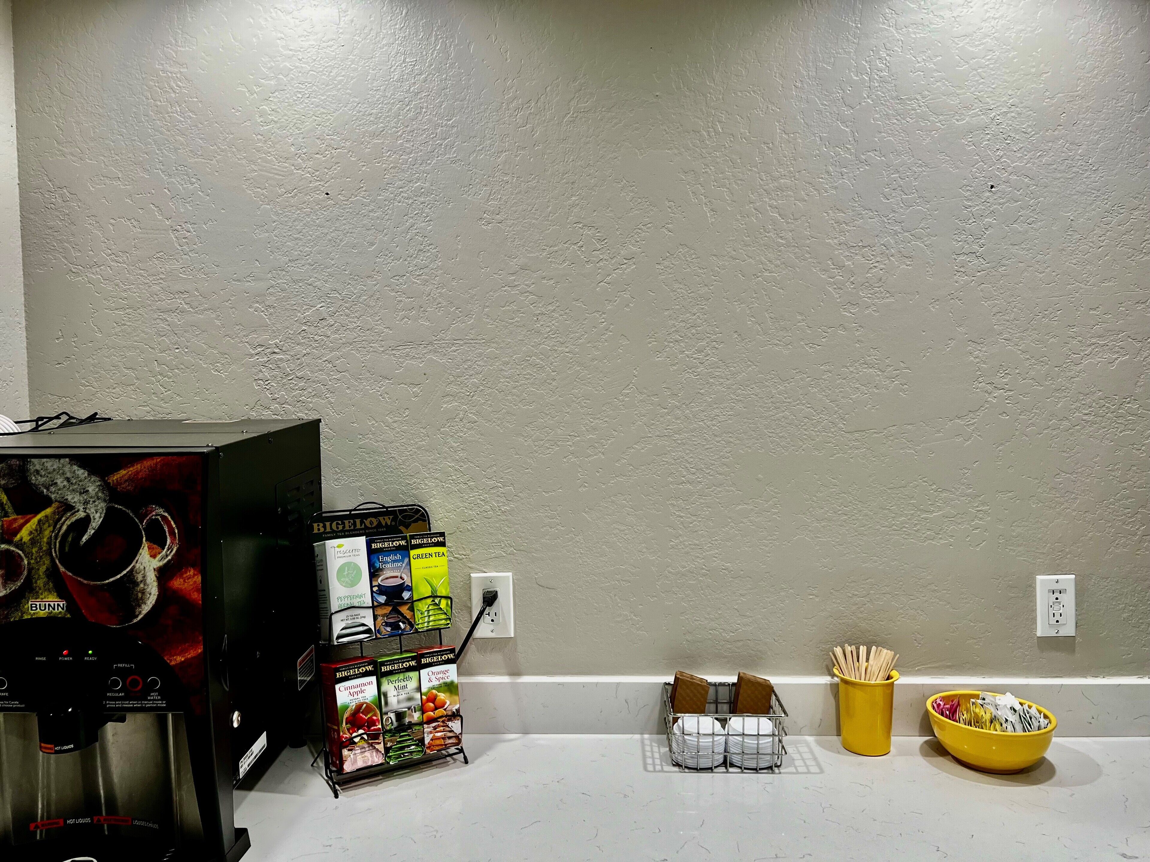 A kitchen area with a coffee machine, tea bags, and utensils.