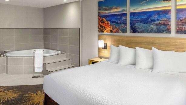A modern hotel room with a large bed, a bathtub, and a view of a canyon.