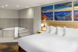 Une chambre d’hôtel moderne avec un grand lit, une baignoire et une vue sur un canyon.