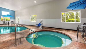 An indoor swimming pool with a blue umbrella, a wheelchair, and a view of greenery outside.