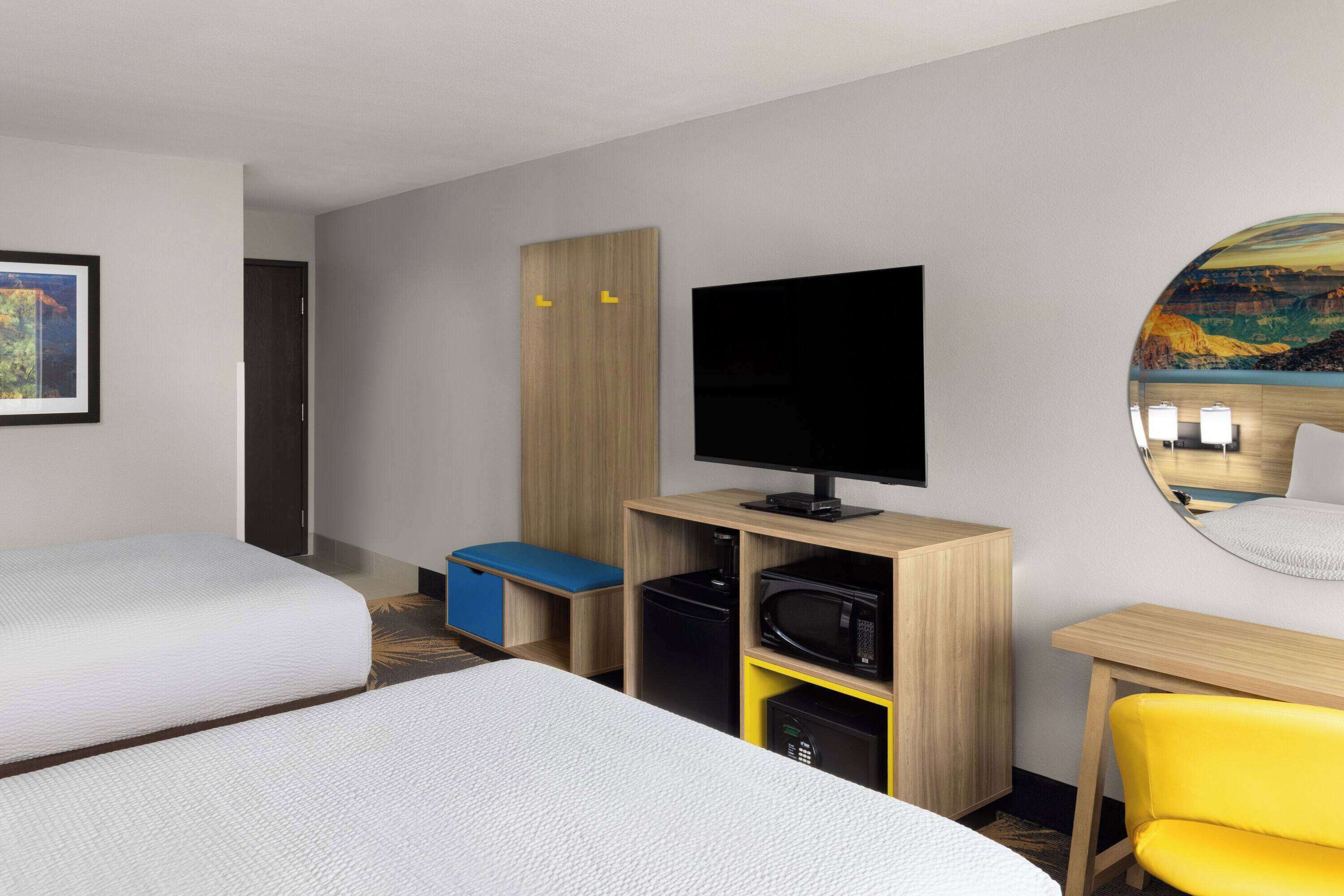 Habitació d'hotel amb dos llits, televisió, escriptori i una cadira.