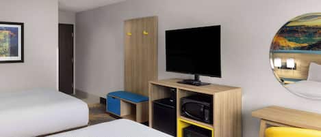 A hotel room with two beds, a television, a desk, and a chair.
