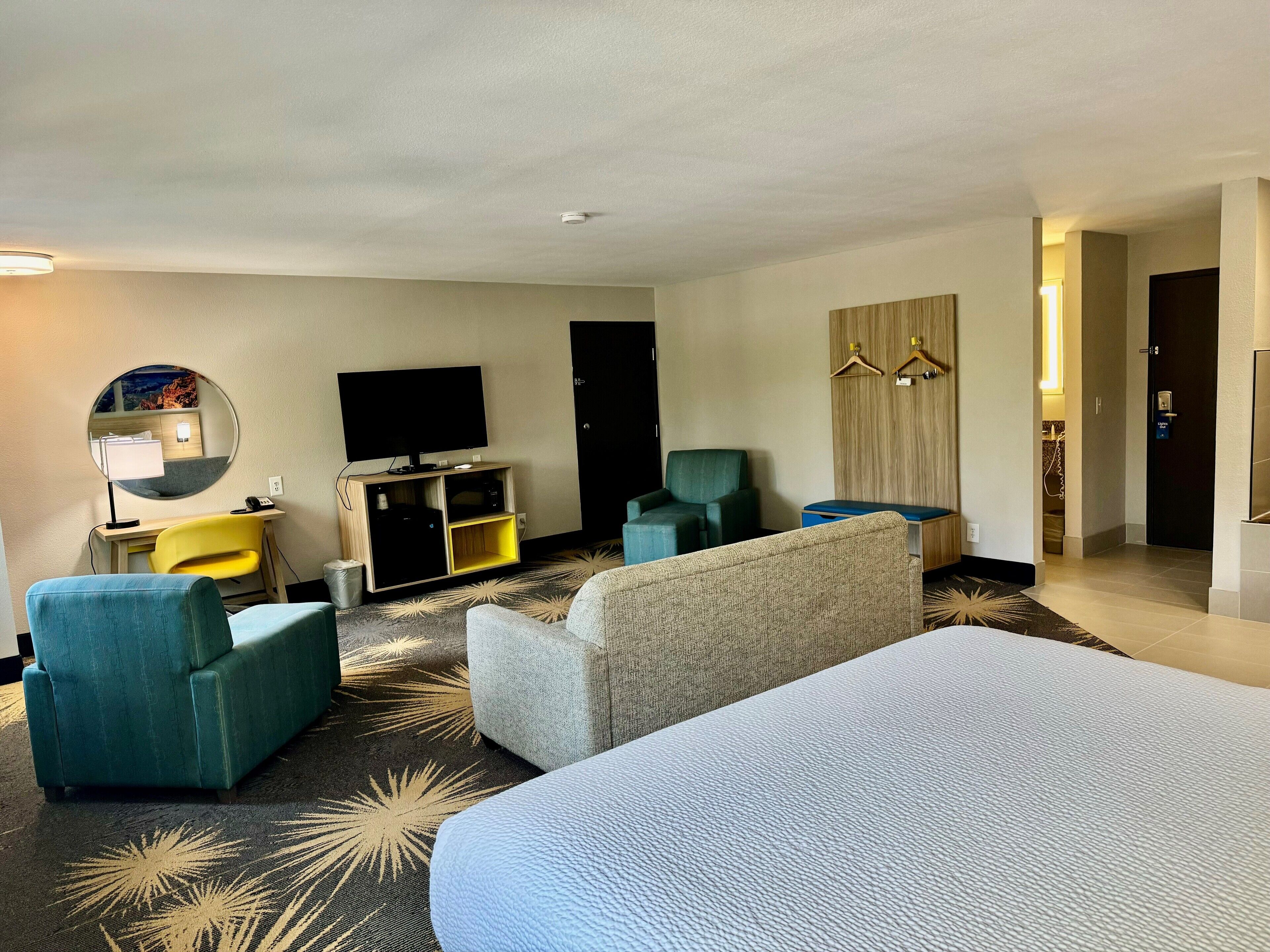 Een hotelkamer met een bed, een bureau met stoel, een televisie, een spiegel en een bank.