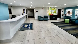 A reception area with a reception desk, two armchairs, a small table with a vase, and a door leading to another room.