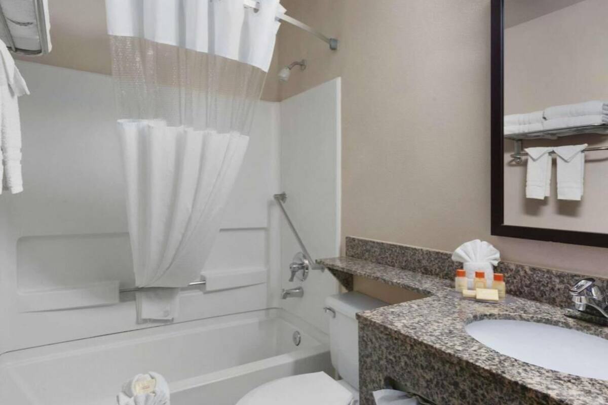 A bathroom with a shower, toilet, sink, and towel rack.