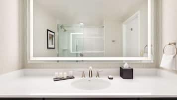 Een moderne badkamer met een grote spiegel, een witte wastafel en donkere kastjes.
