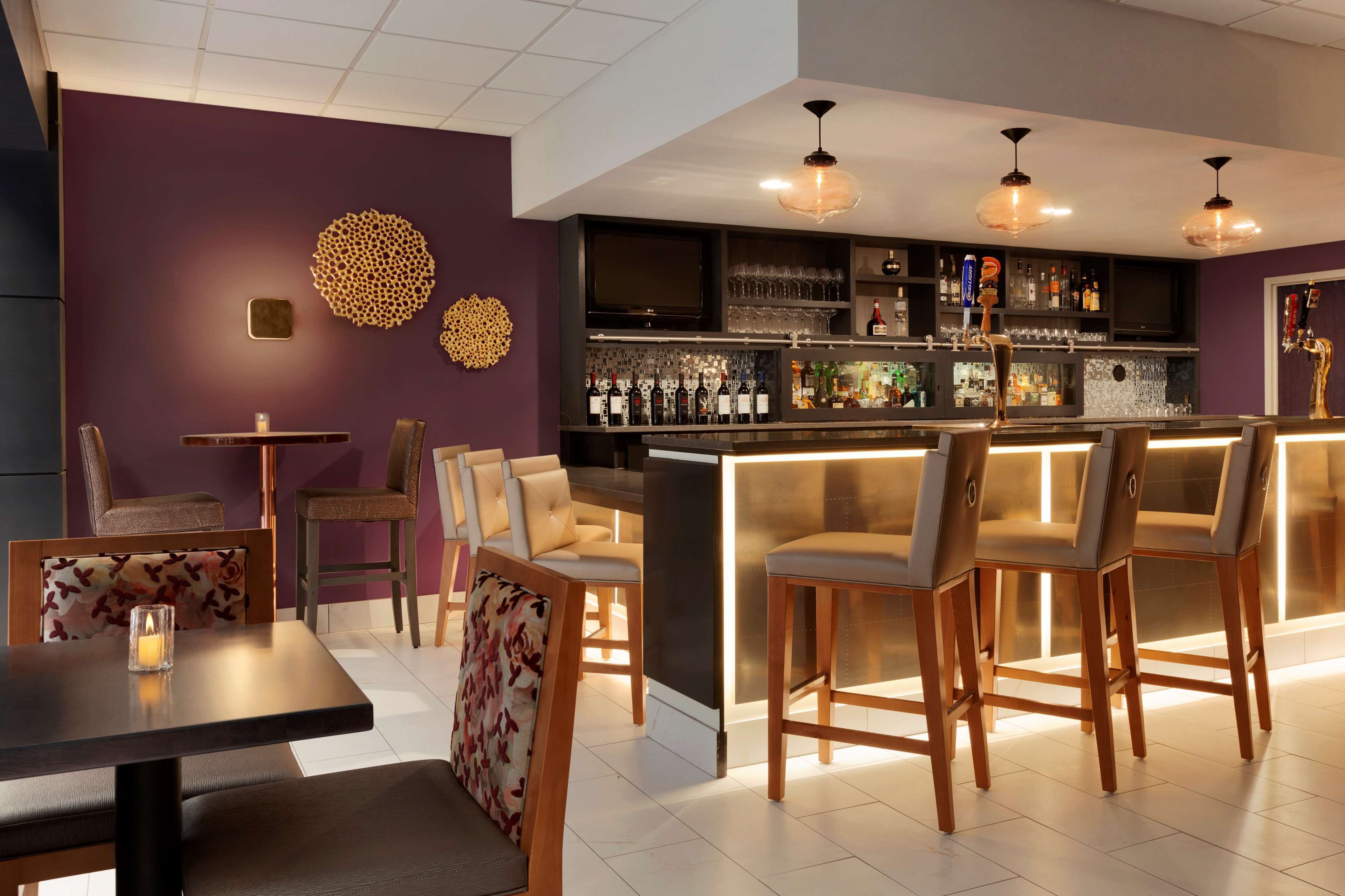 A bar area with a counter, bar stools, and a television screen.
