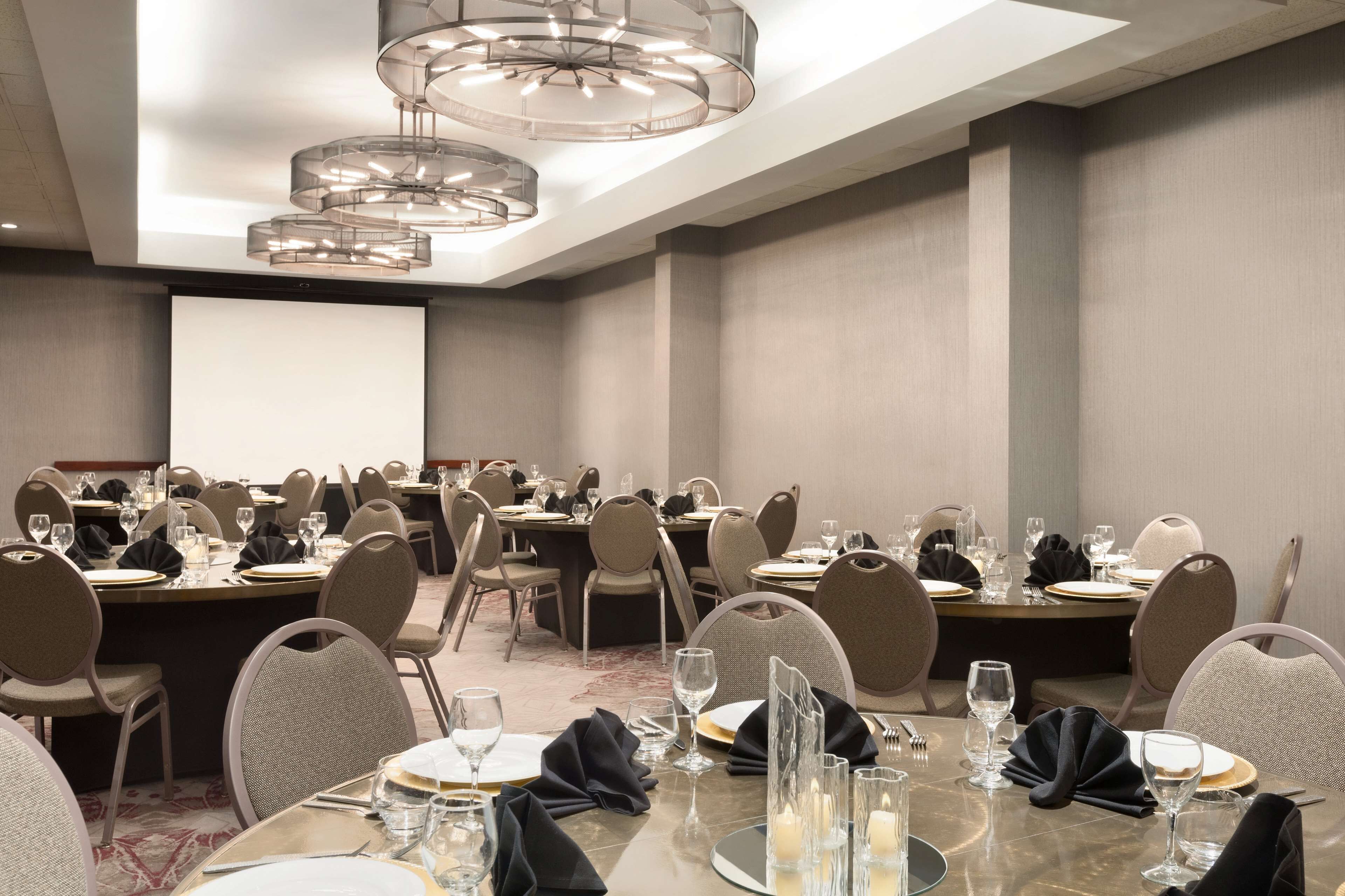 A conference room with multiple tables set for dining, equipped with chairs and glassware.