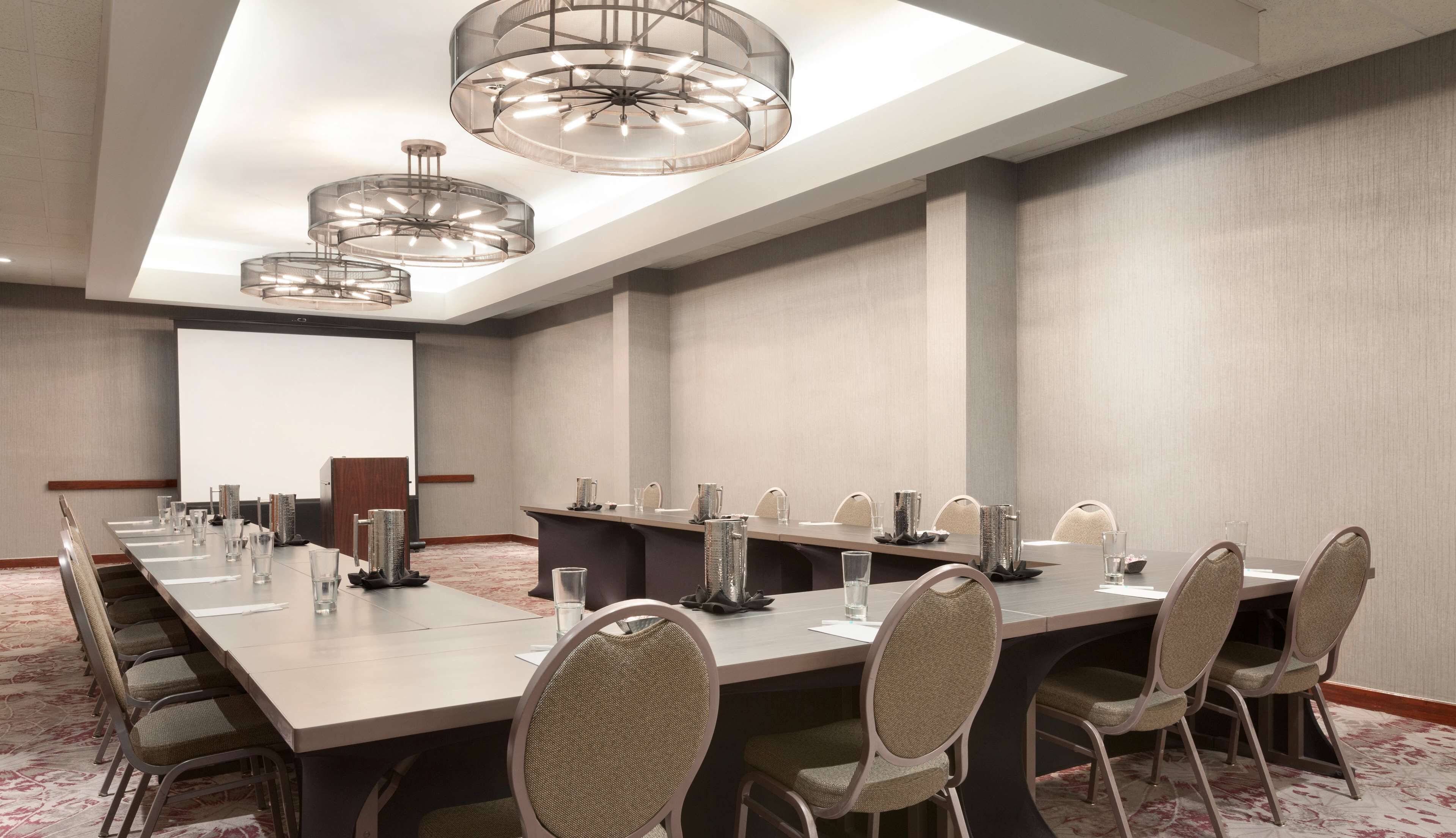 A conference room with a long table, chairs, and a projector screen.