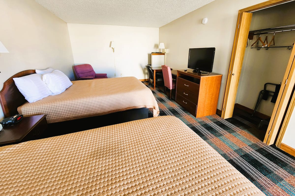 A hotel room with two beds, a desk, a television, and a wardrobe.