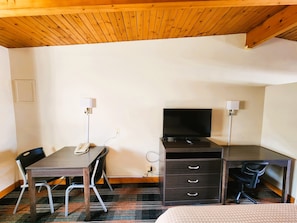 A hotel room with a wooden ceiling, a desk with a computer, a TV, a chair, and a bed. - Countryside Inn Iola (Iola)