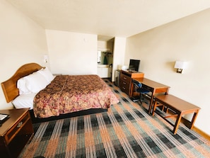 Ein Hotelzimmer mit Bett, Schreibtisch, Stuhl, Fernseher und Lampe.