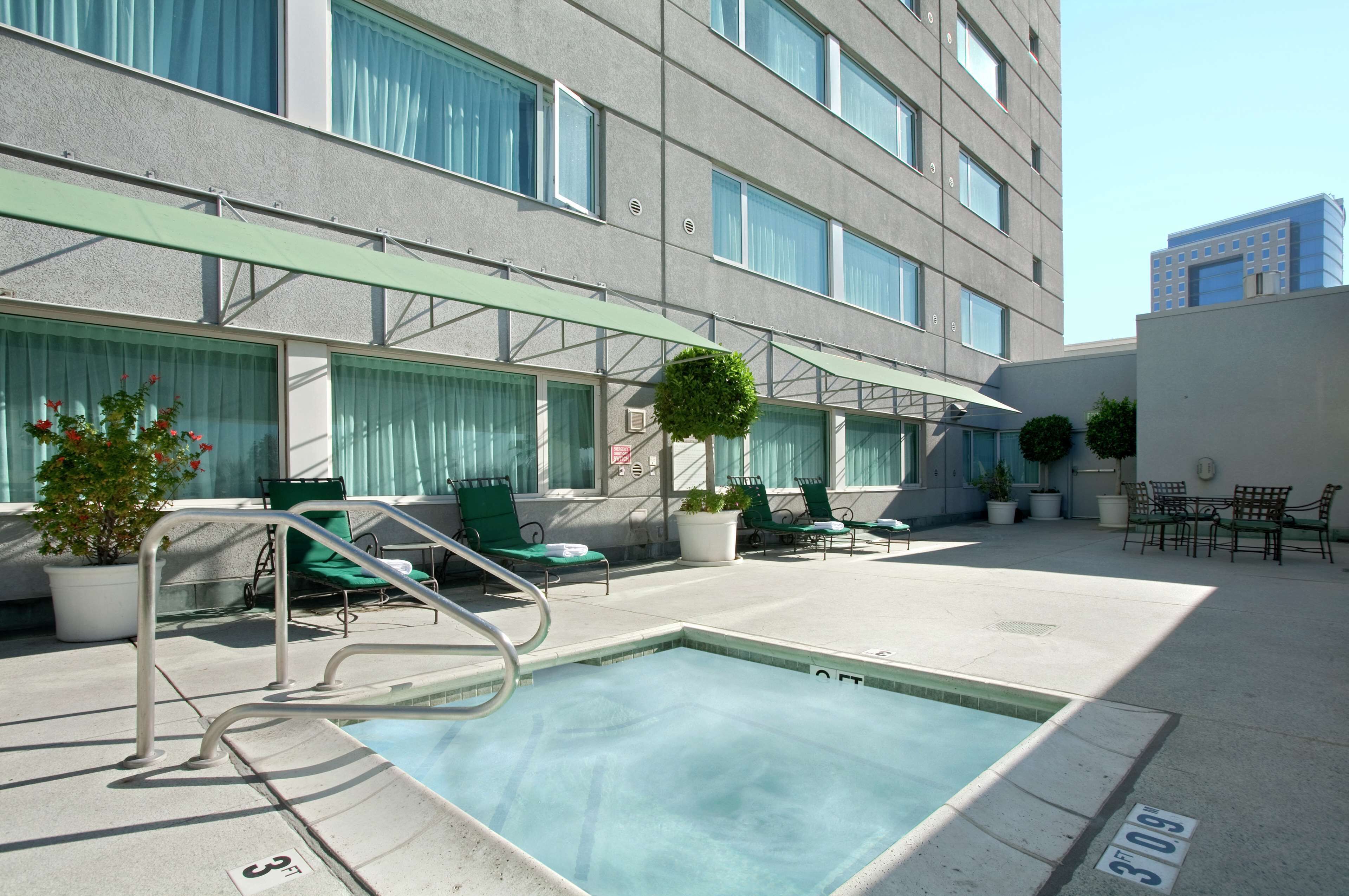 A pool area with a pool, lounge chairs, and potted plants.