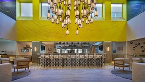 Un vestíbulo amplio con una zona de bar central, diversas opciones de asientos y una lámpara de techo original.