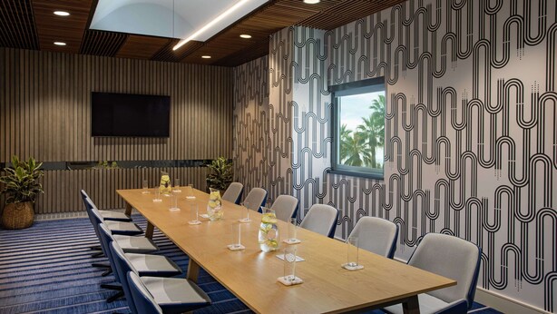 A conference room with a long table, chairs, a TV, and patterned walls. - Hilton San Jose (San Jose)