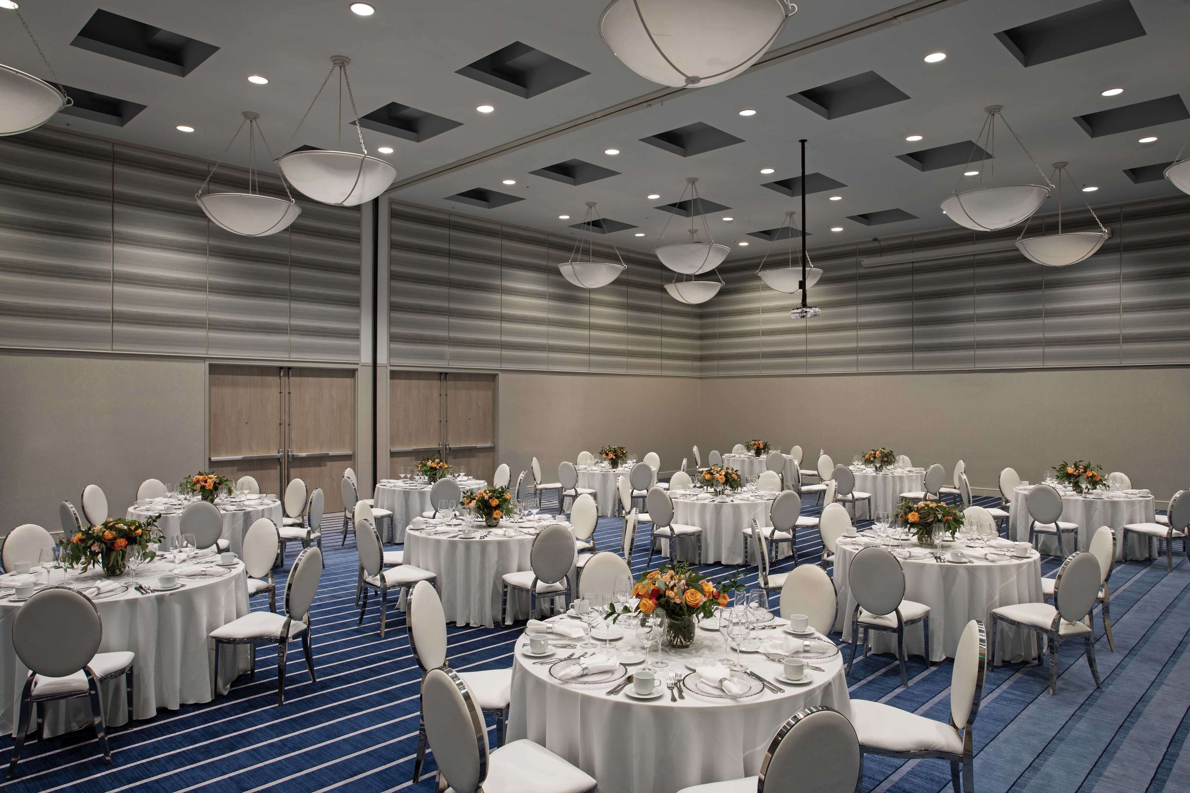 A conference room with round tables, white chairs, and overhead lighting.