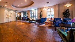 A spacious room with wooden flooring, a round ceiling feature, and a seating area with sofas and a table.
