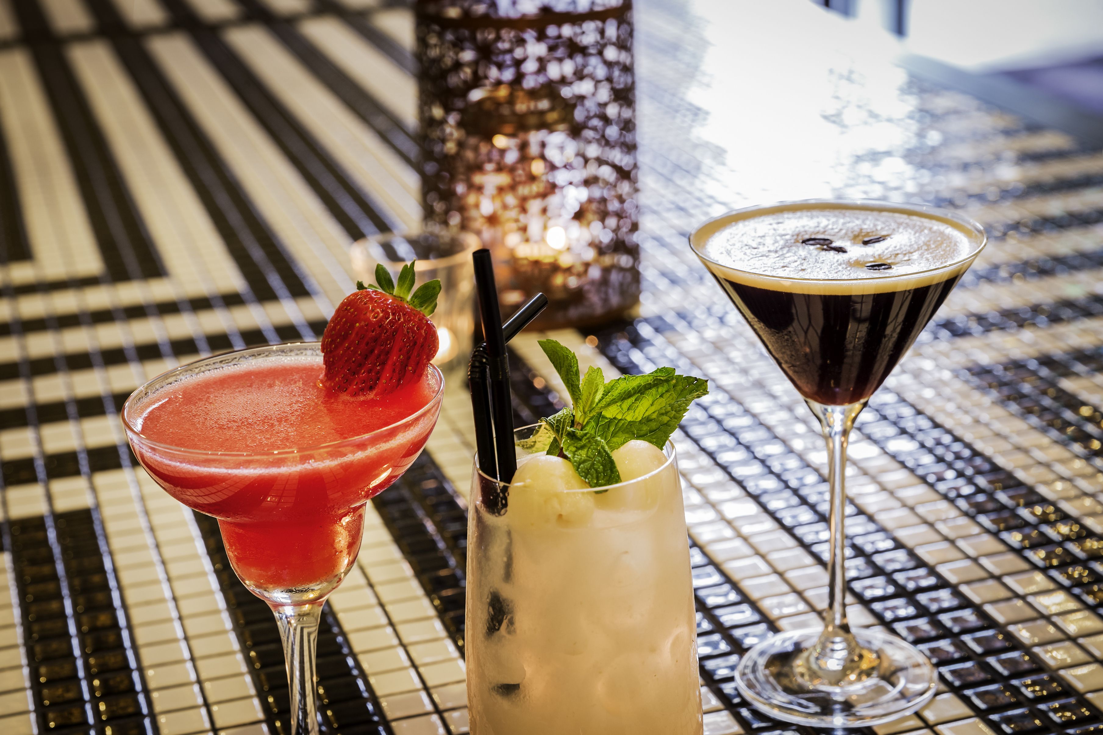 Three cocktails on a tiled bar counter.