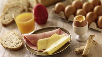 A breakfast setting with bread, eggs, cheese, and a glass of orange juice on a wooden table.