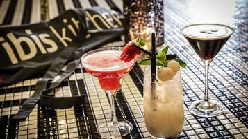 Et barområde med et ternet gulv, en cocktail pyntet med jordbær, og et martiniglas.