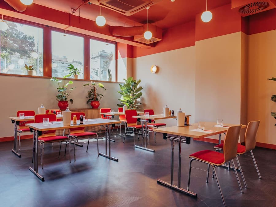 A modern conference room with tables, chairs, and potted plants.