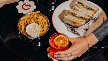 A tray with sandwiches, fries, and a drink, held by hands.