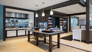 A modern kitchen area with a buffet table, a stainless steel range hood, and a variety of food items displayed. - Hilton Garden Inn Daytona Beach Oceanfront (Daytona Beach)