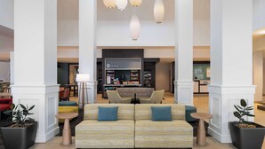 A spacious lobby with a central seating area, a reception desk, and a shop. - Hilton Garden Inn Daytona Beach Oceanfront (Daytona Beach)
