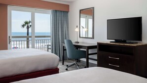 A hotel room with two beds, a desk with a TV, a chair, and a large window overlooking the sea. - Hilton Garden Inn Daytona Beach Oceanfront (Daytona Beach)