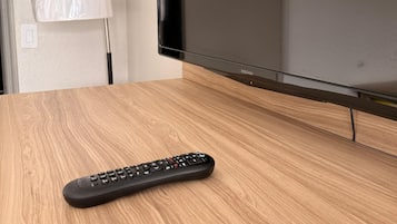 A wooden table with a remote control and a flat-screen TV.
