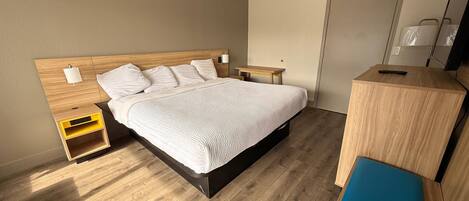 Une chambre d’hôtel moderne avec un lit en bois, des tables de chevet, un bureau et un banc.