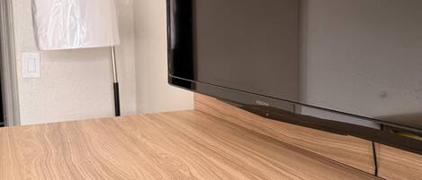 A television on a wooden surface with a remote control in front.