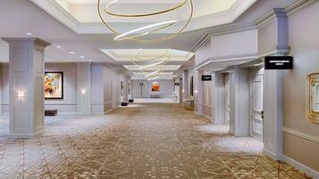 A spacious hallway with a patterned carpet, modern lighting fixtures, and directional signs.