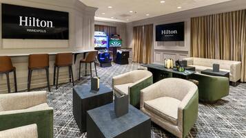 A hotel lobby with seating, a bar area, and a television screen displaying the hotel's name.