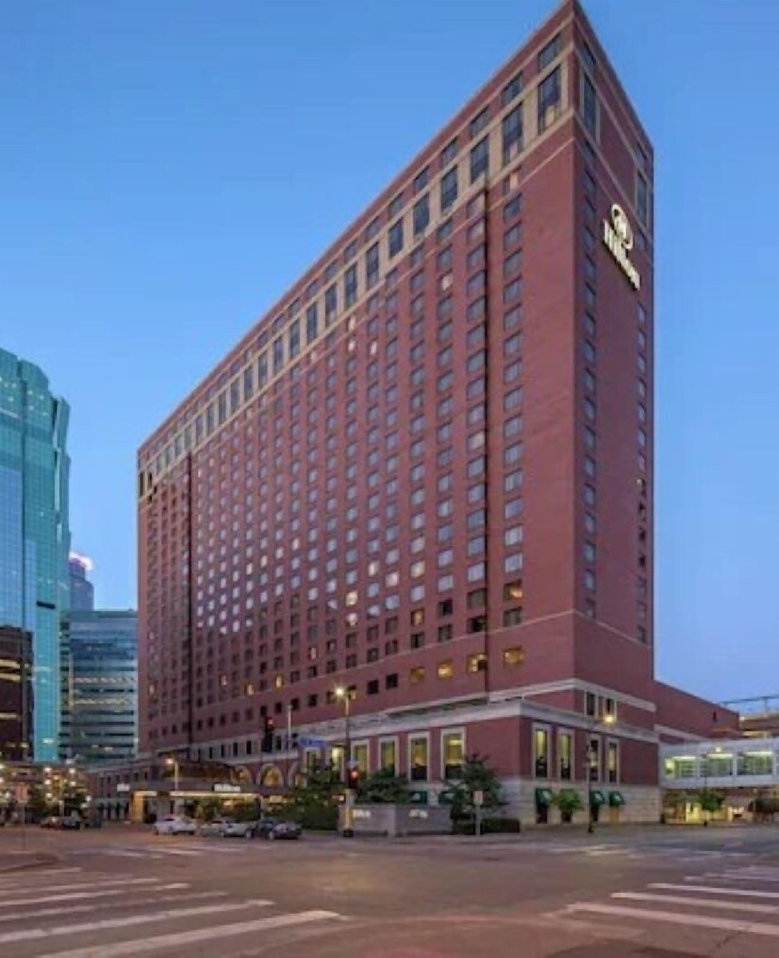 A large, red-brick hotel with a classic design, featuring a prominent 'Hilton' sign on the corner.
