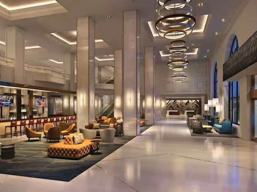 A spacious lobby with a bar area, seating arrangements, and a staircase leading to upper levels.