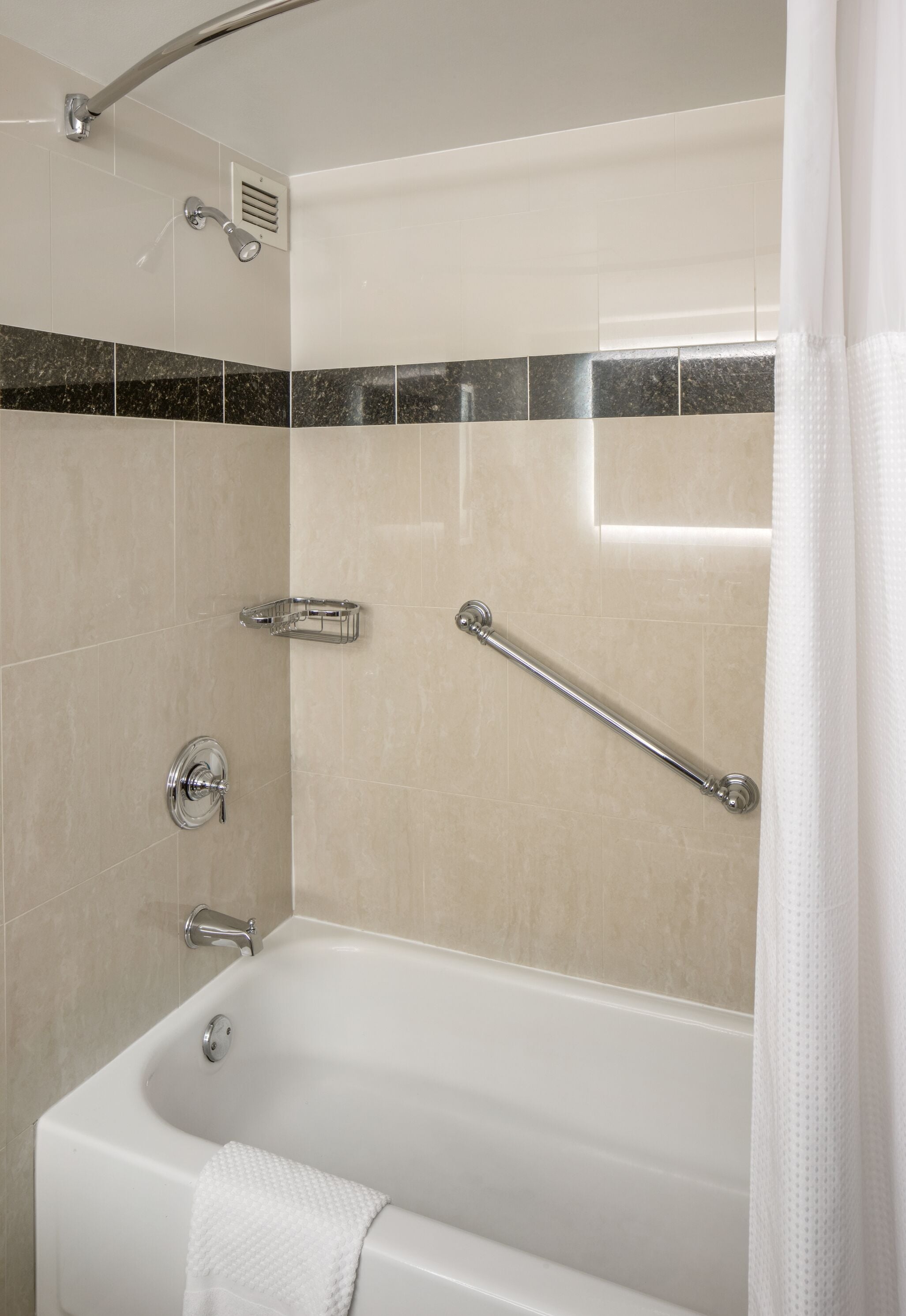 Een badkamer met een badkuip, een douche en een handgreep.