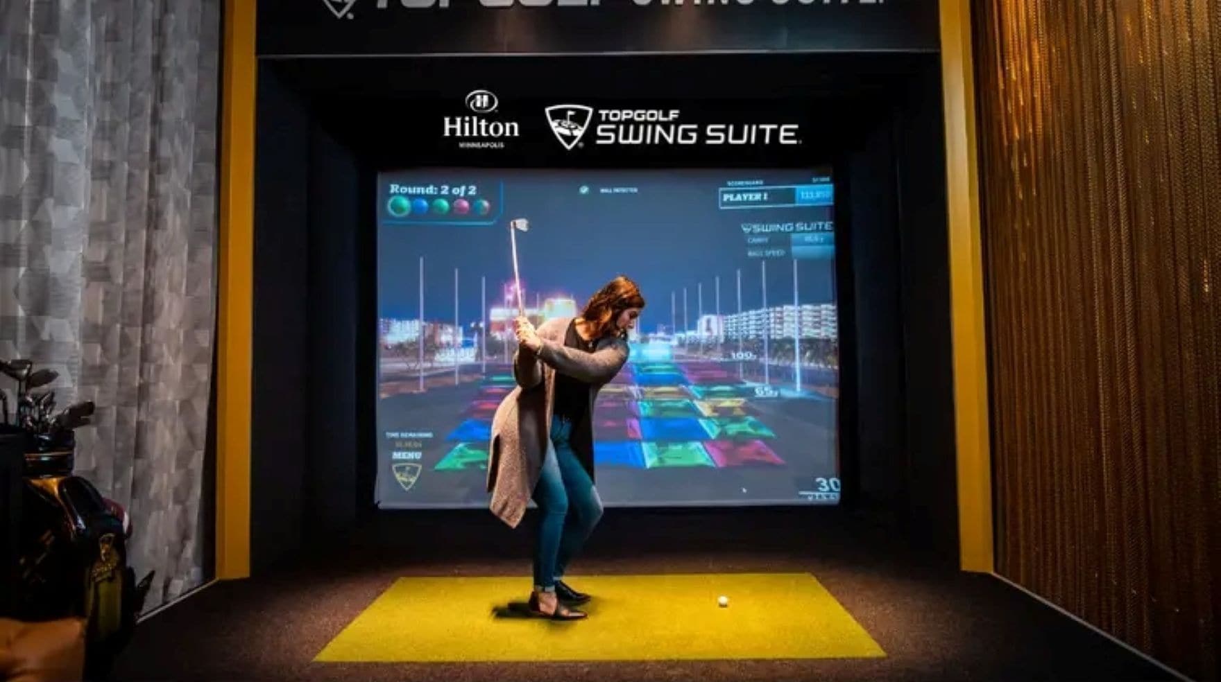 Uma pessoa jogando um jogo de golfe em vídeo em frente a uma tela que mostra um campo de golfe.