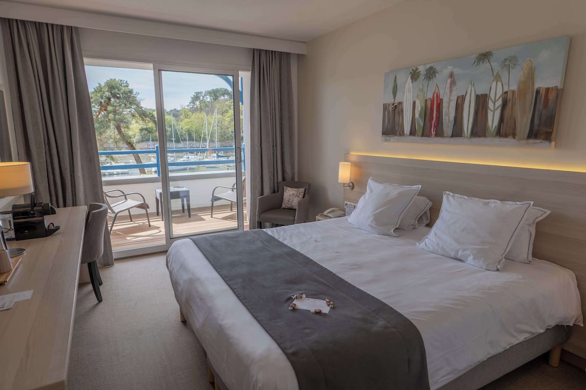 Habitación de hotel con una cama grande, un escritorio, una silla y vistas al exterior.