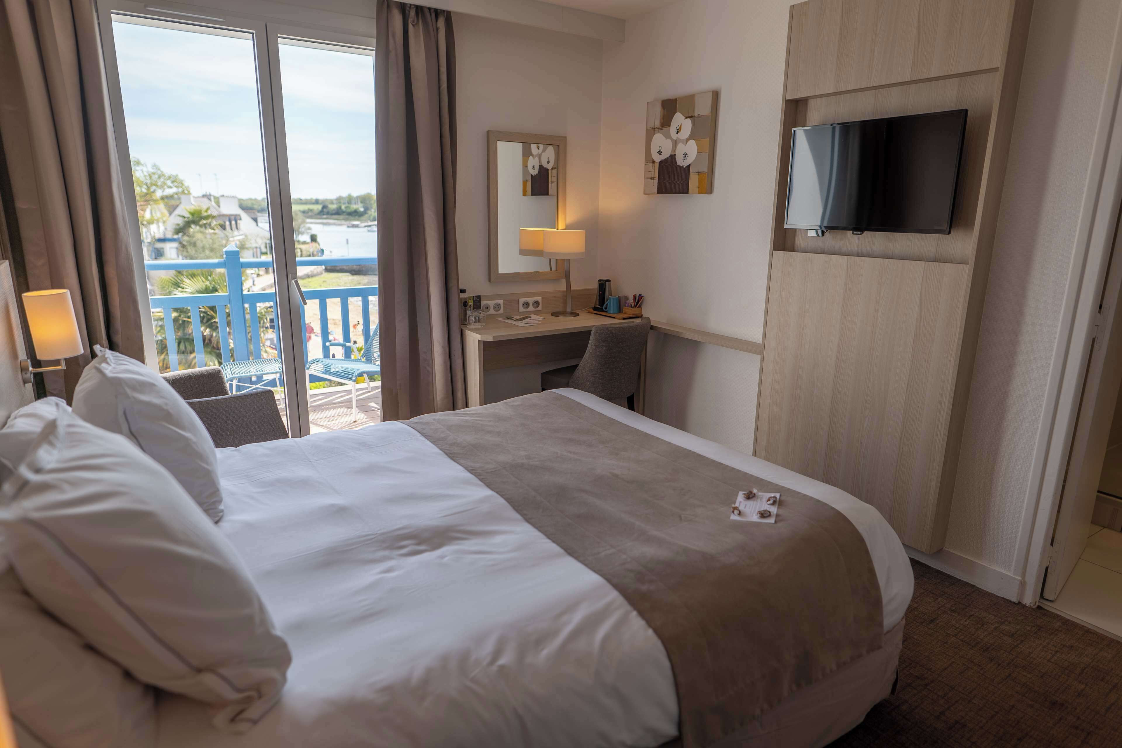 Een hotelkamer met een groot bed, een bureau, een televisie en uitzicht op water.
