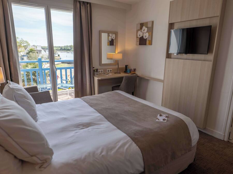 Een hotelkamer met een groot bed, een bureau, een televisie en uitzicht op water.